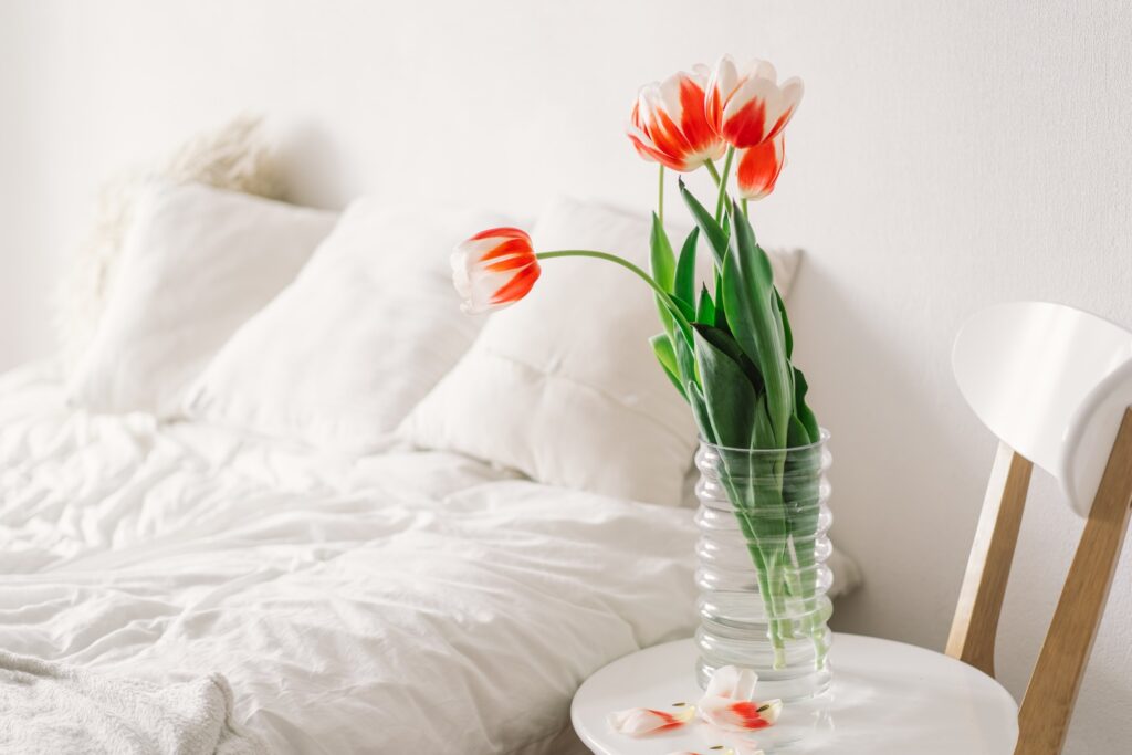 Red flowers in bedroom with white bedding