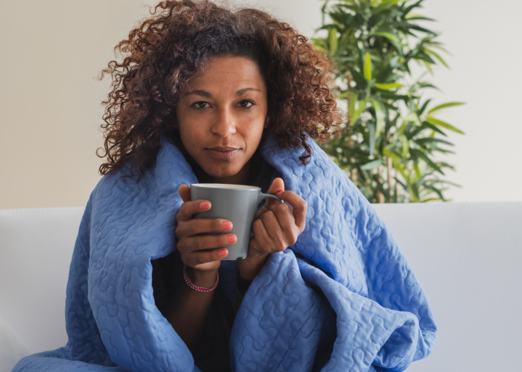 african american woman wrapped in a blanket with a coffee mug in hands